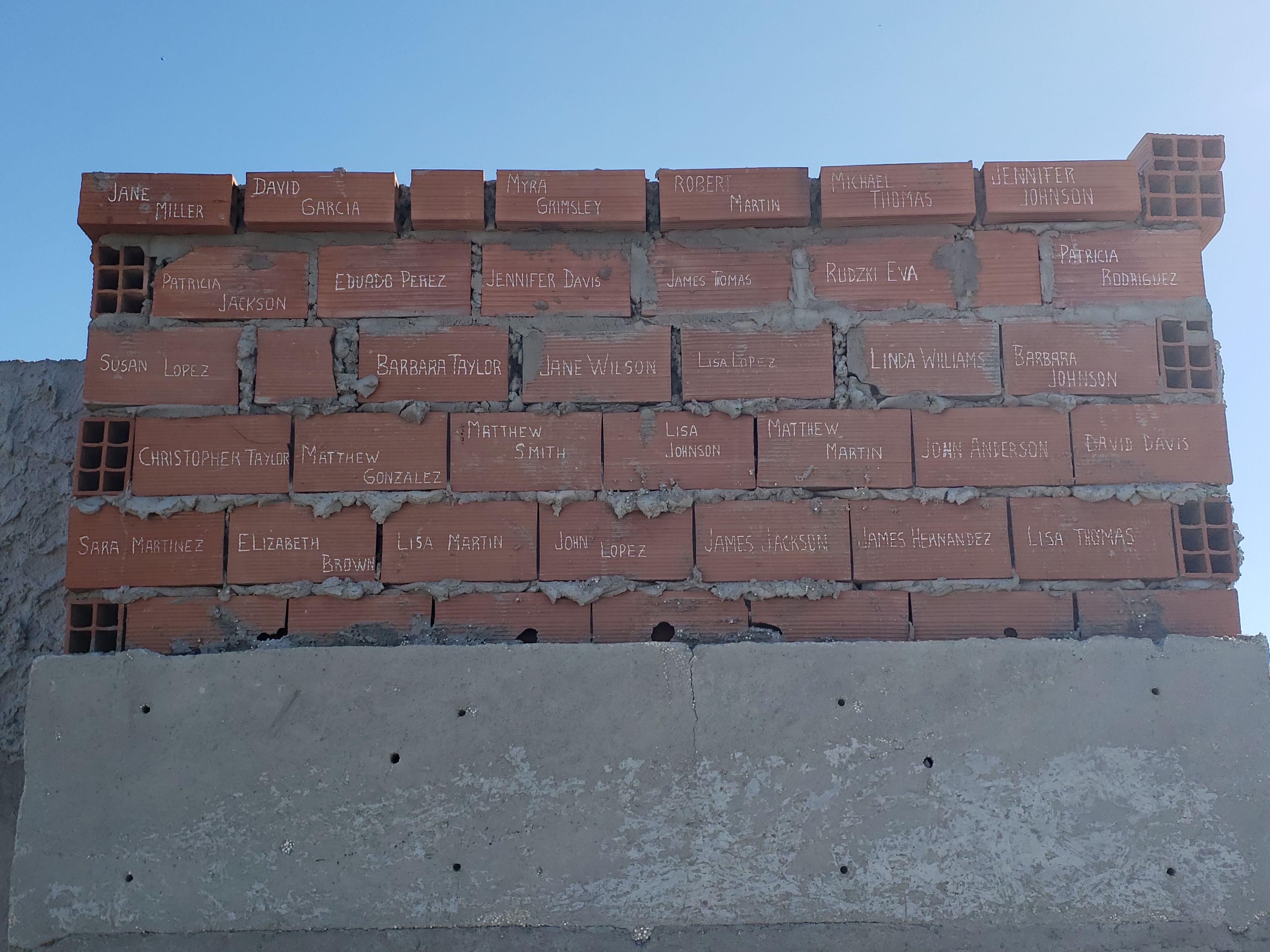 Brick wall with handwritten names sealed into the structure